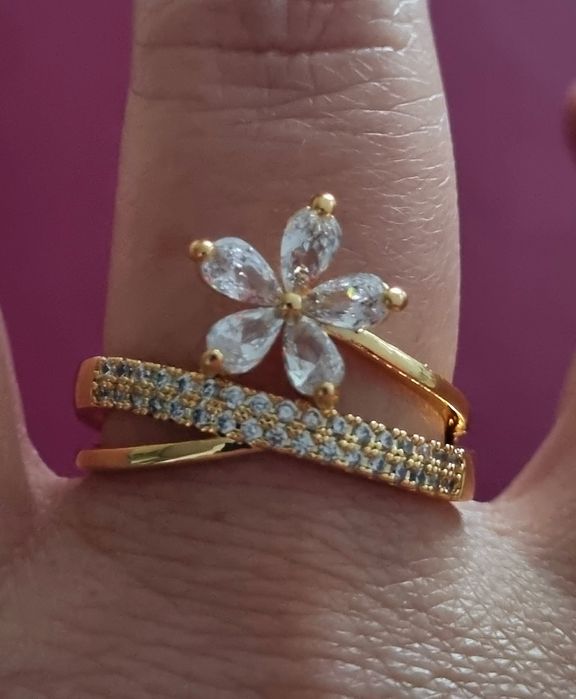 Anel dourado, em aço, com zirconias e uma flor. T17 e T20