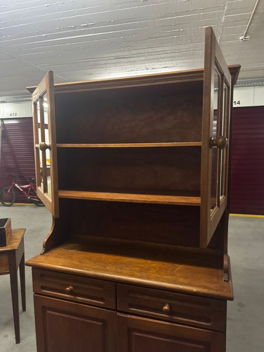 traditional cherry wood hutch with glass doors and storage below.