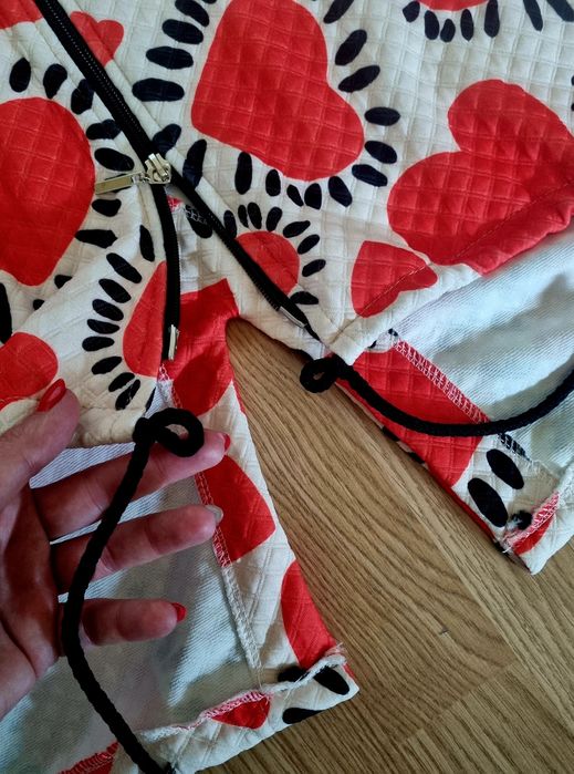 Casaco comprido com corações vermelhos em fundo branco.  TU