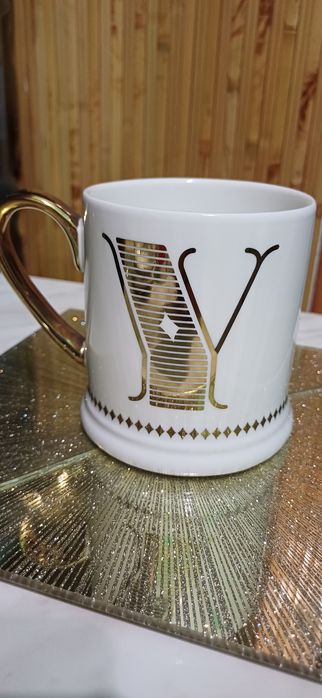 Белая кофейная кружка Tesco с золотым декором и инициалом «Y».
