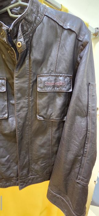 мужская коричневая кожаная куртка с карманами на груди и рукавах.
