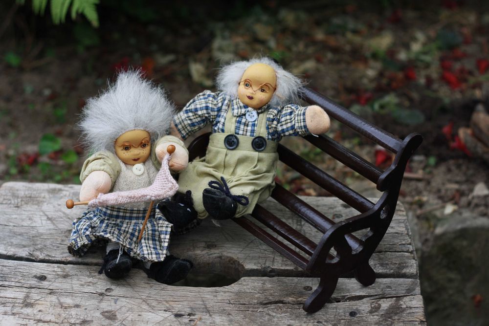 Dwie lalki siedzące na ławce Babcia i Dziadek