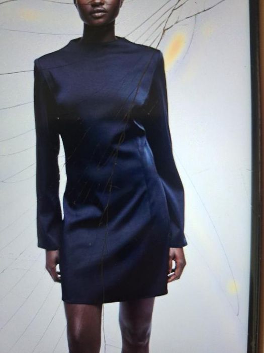 Czarna krótka sukienka z poduszkamin na ramionach i wycięciem z tyłu