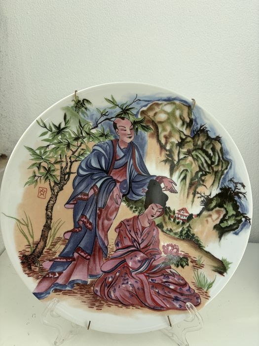 Prato decorativo em porcelana chinesa representando figuras.