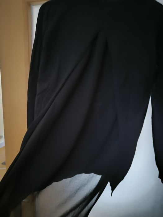 Camisola preta pedras de brilho e abertura com transparência atrás.