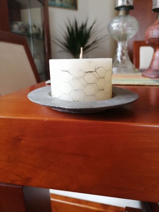 Vela branca rodeada com metal e com suporte metálico