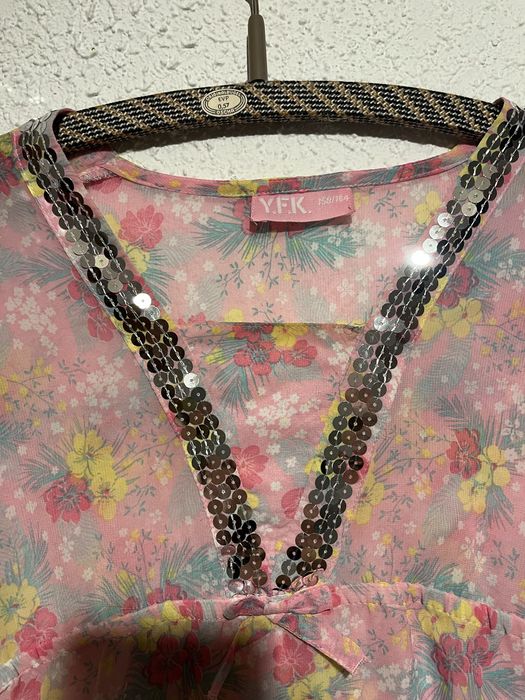 Różowa bluzka z kwiatowym nadrukiem i cekinami.