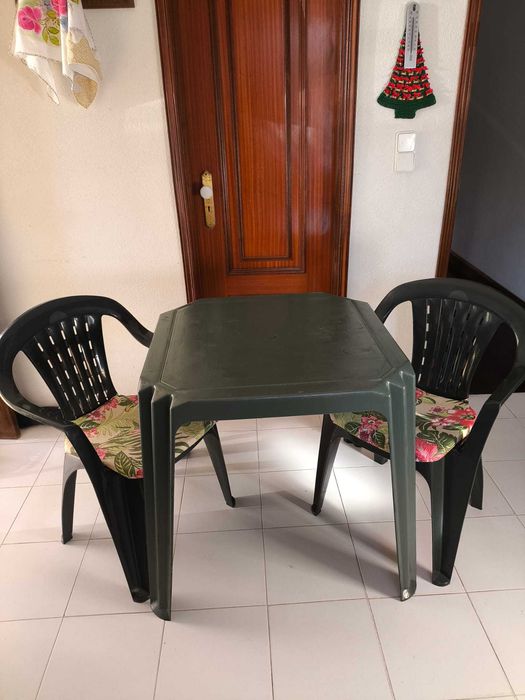 Mesa com 2 cadeiras de plástico na cor verde