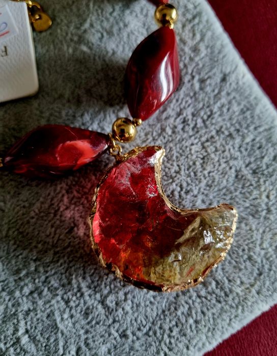 Colar dourado, em aço, com peças bordeaux em acrílico e uma meia lua.