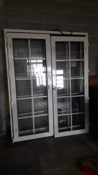 Várias janelas de alumínio branco e portadas metálicas interiores.