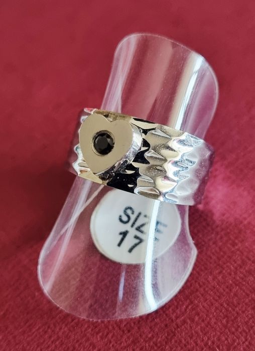 Anel prateado, em aço, com 1 coração com pedrinha preta no centro. T17