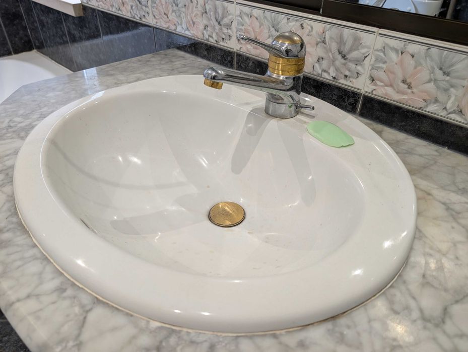 Lavatório de cerâmica embutido em móvel de mármore com gavetas