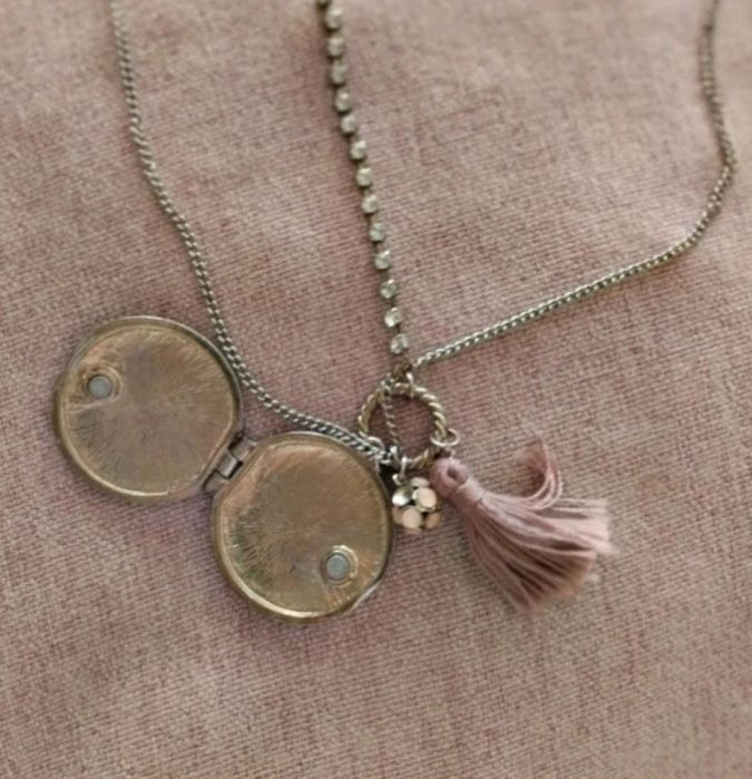 Colar com medalhão floral e borla rosa.