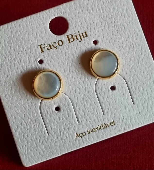 Brincos dourados, em aço, com pequena peça redonda em madrepérola. De pico