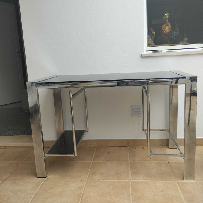 Mesa de escritório em vidro e cromo. Dimensões: comprimento 120 cm, largura 60 cm, altura 76 cm.