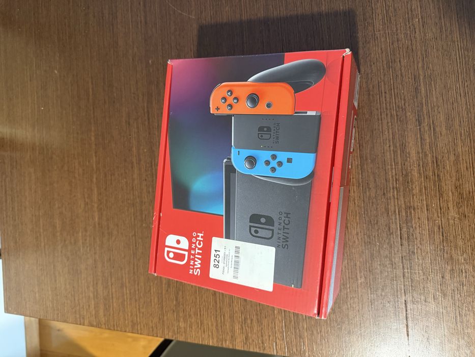 Vendo Nintendo Switch clássica com comandos Joy-Con azul e vermelho, em estado novo.