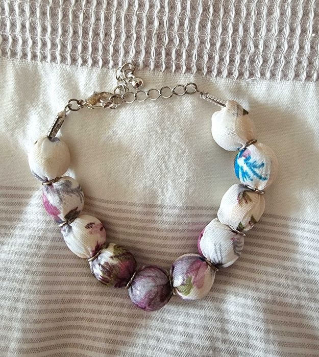 Pulseira branca com tecido com padrão em tons de lilás e verde