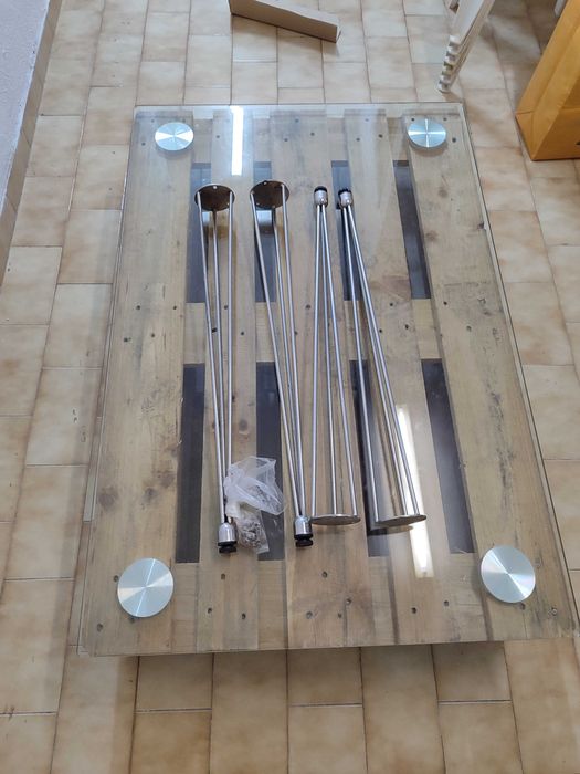 Mesa de vidro com pés de ferro e duas paletes de madeira