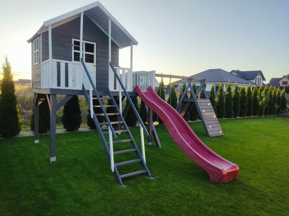 Duży drewniany domek dla dzieci ze zjeżdżalnią, huśtawkami, wspinaczką