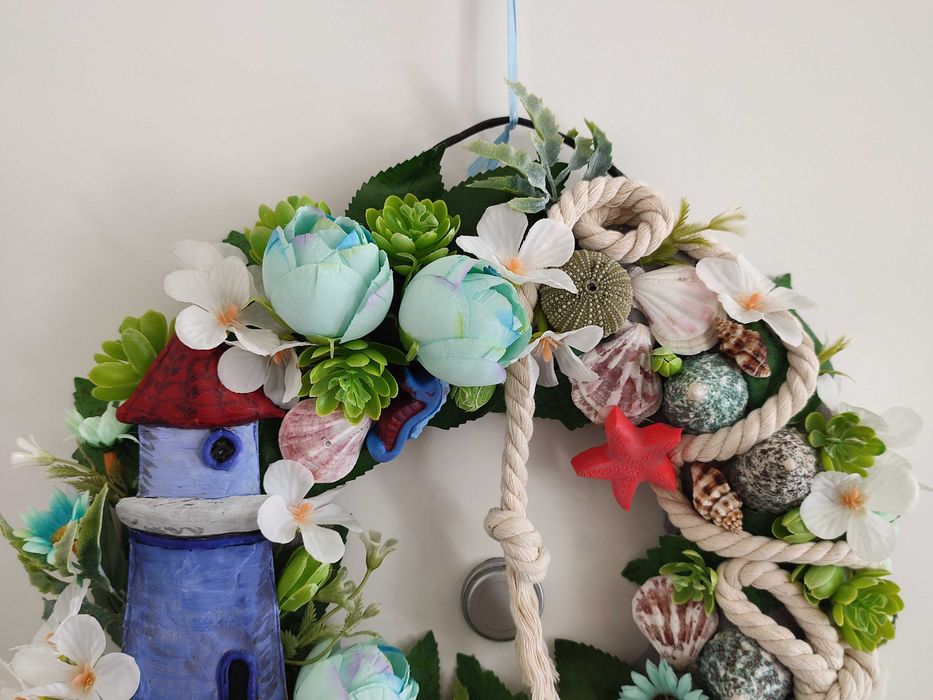 Guirlanda artesanal marítima com flores, conchas e farol decorativo