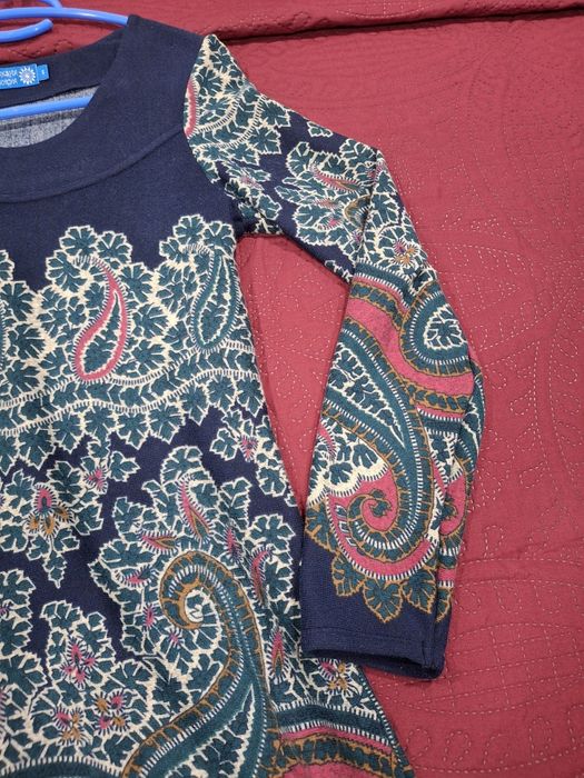 Vestido com um padrão floral e paisley vibrante.

- Decote redondo.
- Mangas compridas.
- Padrão paisley em azul, verde e rosa.