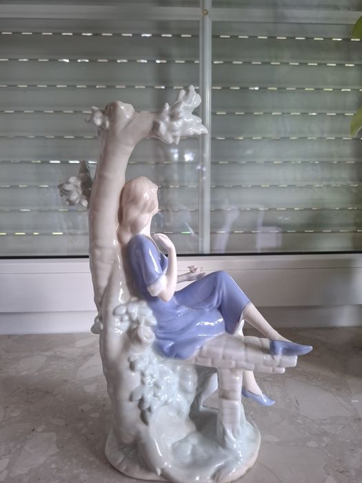Piękna porcelanowa figurka dziewczyna siedząca na drzewie