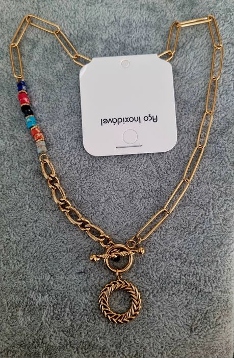 Colar dourado, em aço, assimétrico e com pedrinhas naturais coloridas.