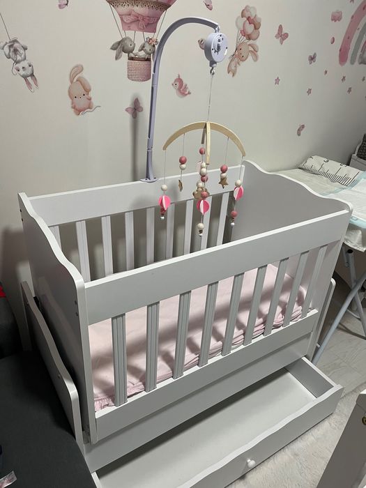 Berço de bebê com balanço, com um colchão e um trocador de fraldas.