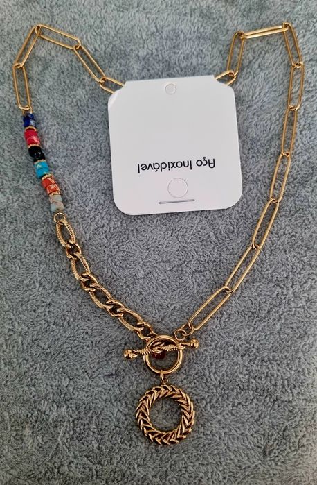 Colar dourado, em aço, assimétrico e com pedrinhas naturais coloridas.