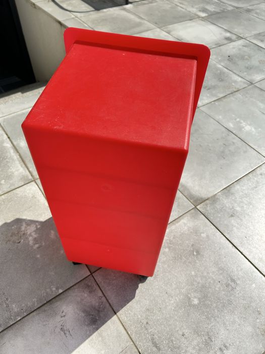 Pequeno móvel de plástico vermelho, com rodas, prateleira e 2 gavetas