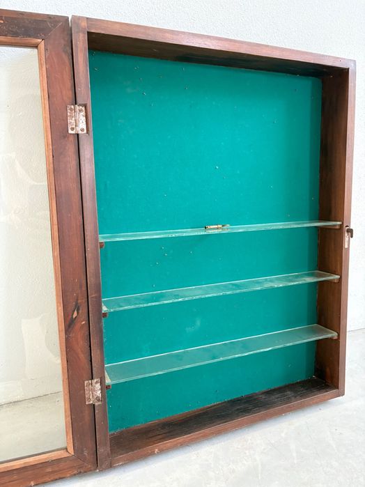 Escaparate com fundo verde e  prateleiras em vidro e porta de vidro