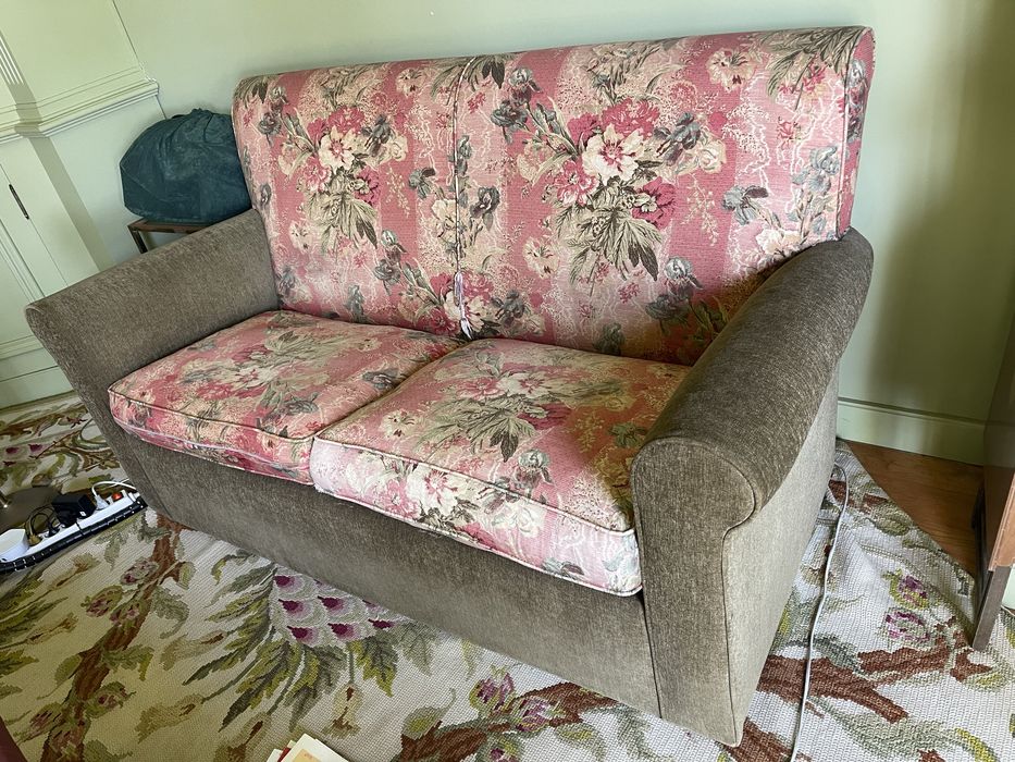 Sofa de 2 lugares em verde e com padrao de flores rosa.