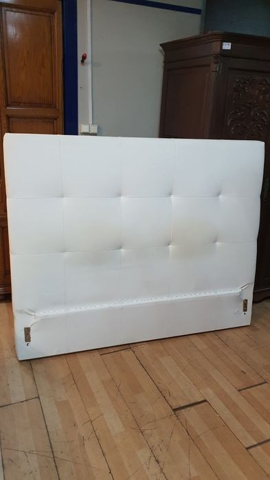 Cama estofada e mesinhas com marcas de uso estrado