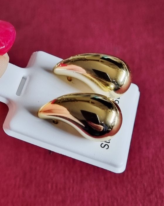 Pequenos brincos dourados, em aço, em forma de gota. De pico