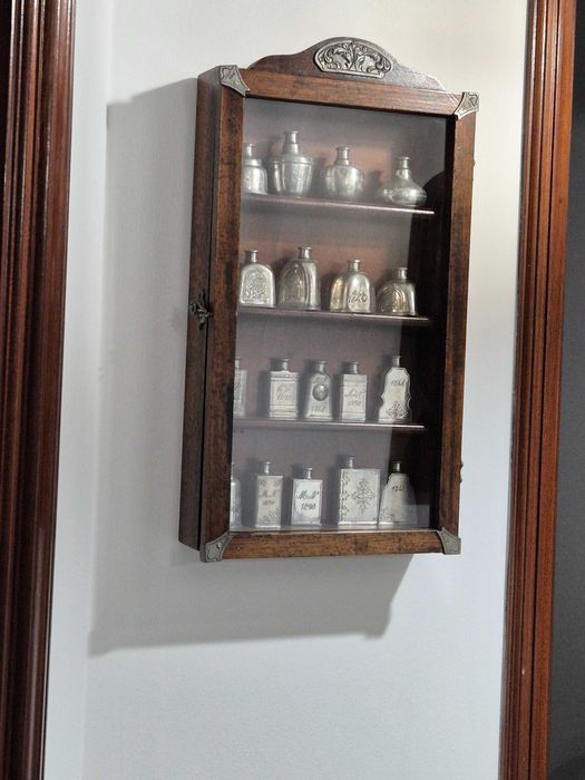 Vitrine com coleção de frascos em estanho