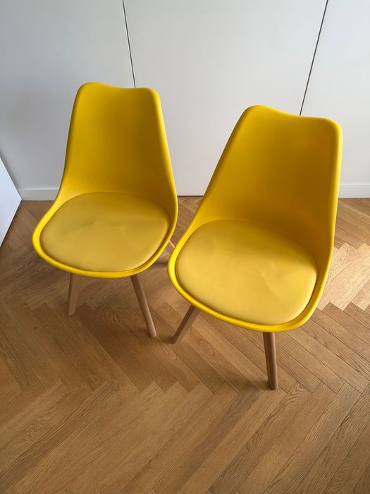 Dwa żółte krzesła na drewnianych nogach skandynawski styl