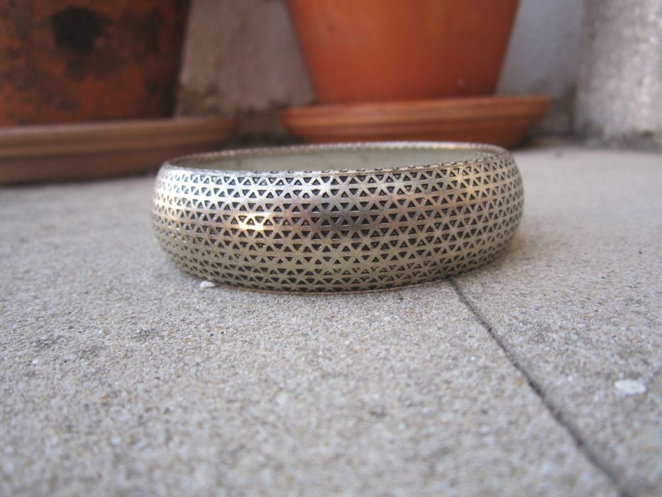 Pulseira rígida prateada com intrincado padrão geométrico triangular perfurado