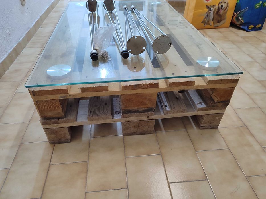 Mesa de vidro com pés de ferro e duas paletes de madeira