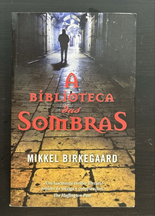 Vendo o livro “A Biblioteca das Sombras”, de Mikkel Birkegaard.