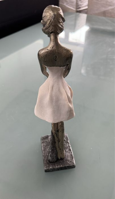 Peça decorativs em formato de mulher com o cabelo a fugir com o vento.