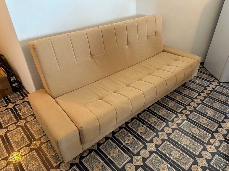 Sofá-cama bege em bom estado.