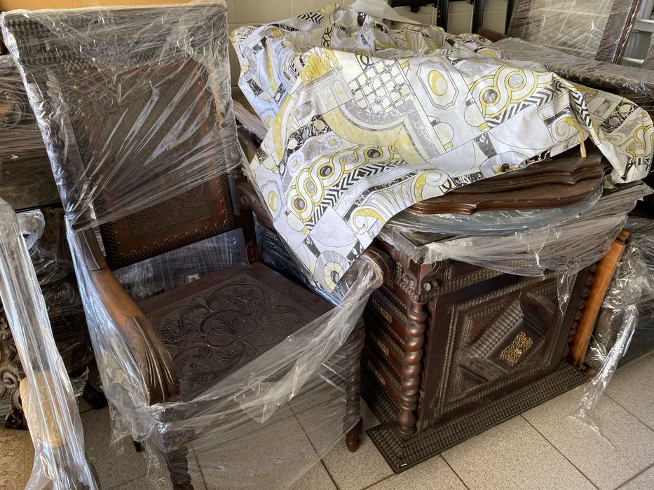 Escritório em Pau Santo, com mesa com tampo de vidro. Um cadeirão e duas cadeiras. Com móvel livros.