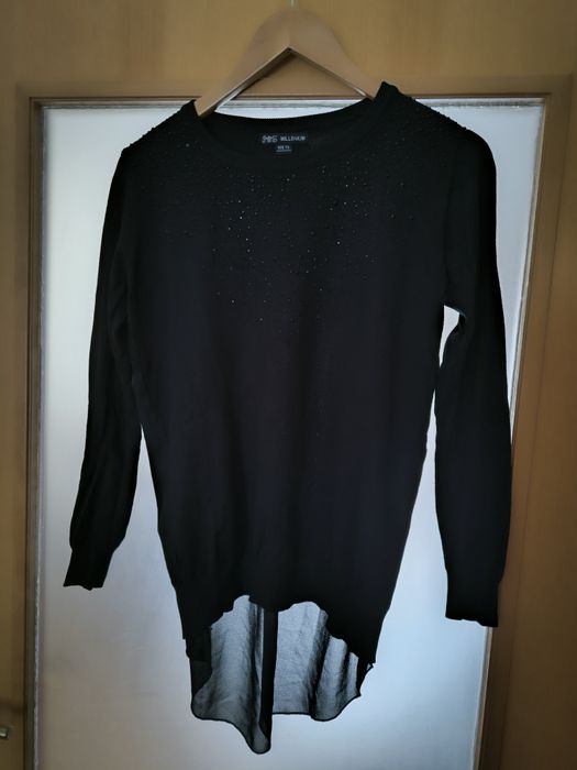 Camisola preta pedras de brilho e abertura com transparência atrás.