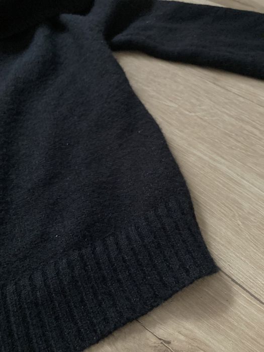 Czarny sweter bez ramion.