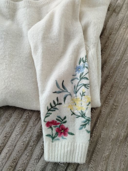 Jasny swetr z haftowanymi rękawami. Rozmiar L/XL