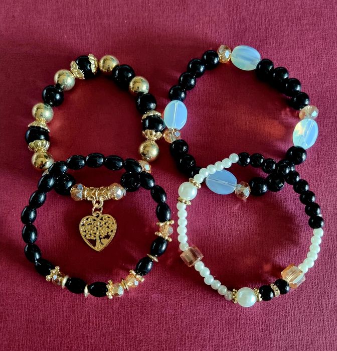 Conjunto de 4 pulseiras elásticas em tons de preto e dourado.