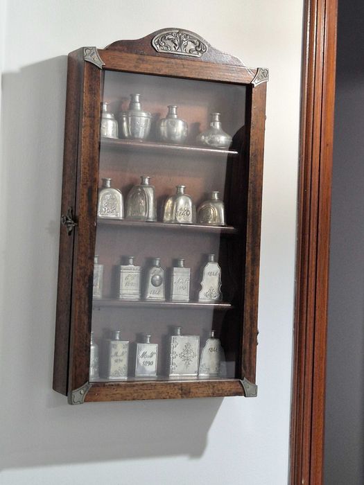 Vitrine com coleção de frascos em estanho