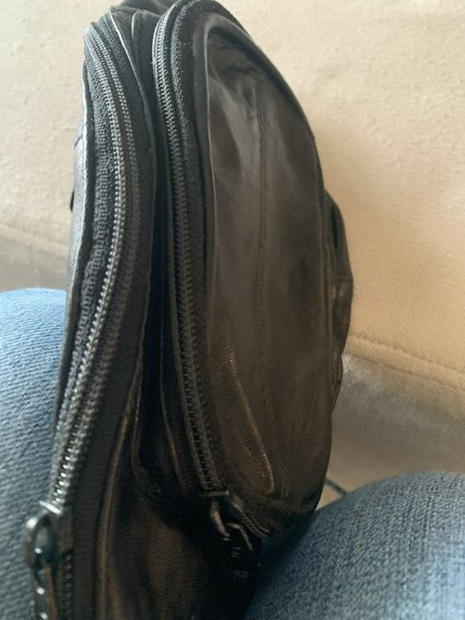 Bolsa de cabedal preta, é uma pochet classica de cintura com fecho.