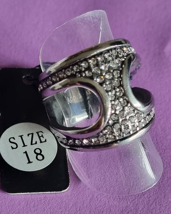 Anel prateado, em aço, aberto dos lados e cheio de zirconias. T17/18