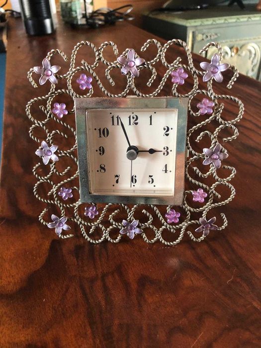 Relógio delicado em moldura trabalhada com flores em metal